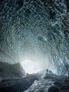 Mountaineer in the ice chapel with meltwater stream