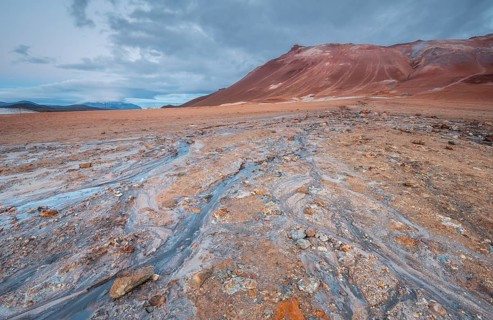 Water from a hot spring flows over the red plain
