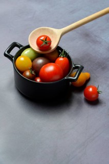 Different cherry tomatoes in pot with cooking spoon