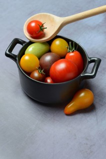 Different cherry tomatoes in pot with cooking spoon