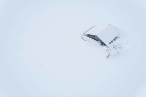 Aerial view of a lonely wooden house in the snow in winter