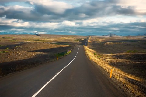 Road in the evening light runs through vuclan plateau with lava rock in the Krafla