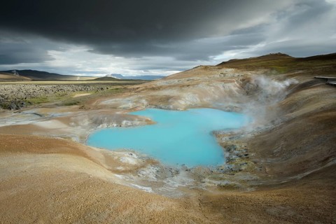 Turquoise lake with dramatic clouds in the lava river Leihrnjukur in the Krafla
