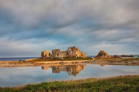 House between granite rocks with water reflection