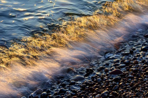 Waves and spray on the beach at sunrise