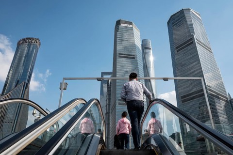 Passers-by on an escalator on a bridge in the financial district of Pudong