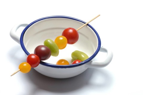 Various cherry tomatoes on wooden skewers on a bowl