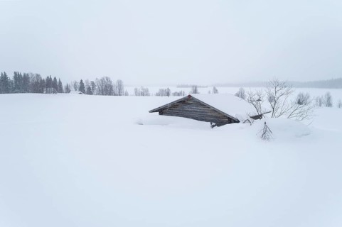 Lonely wooden house in wide landscape in snow in winter
