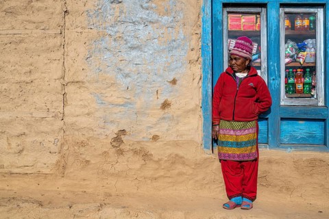 A local woman is standing in front of the window of her shop