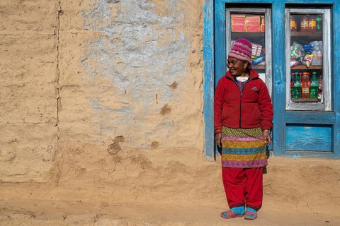 A local woman is standing in front of the window of her shop