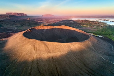 Aerial view of the tuffring crater Hverfjall in the evening light in the Krafla volcano system in the Myvatn region rising out of a green plain