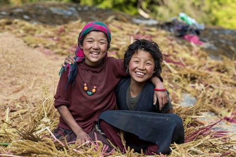 Two happily laughing children sitting in a pile of pearl millet