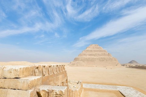 Wall engraved with images of cobra snakes next to stepped pyramid