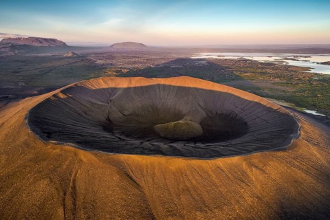 Aerial view of the tuffring crater Hverfjall in the evening light in the Krafla volcano system in the Myvatn region rising out of a green plain
