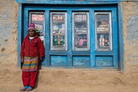 A local woman is standing in front of the window of her shop