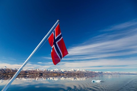 Norwegian flag waving over fjord in Greenland
