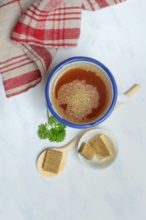 Cup with bouillon broth and bouillon cubes on a wooden spoon