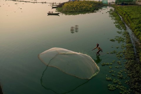 Fishermen on Taung Tha Man Lake throw out a fishing net for sunrise