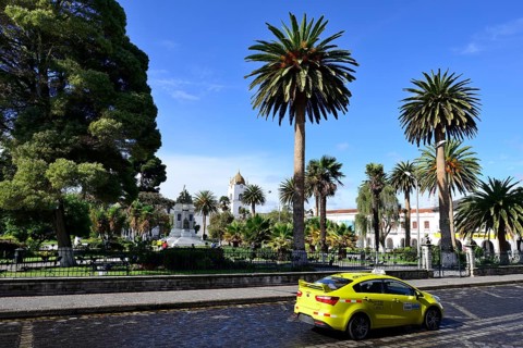 Yellow taxi in front of the Parque Vicente Leon with its monument