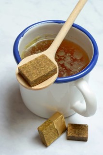 Cup with bouillon broth and bouillon cubes on a wooden spoon