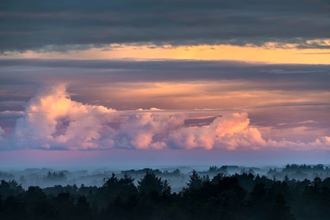 Clouds illuminated by the rising sun and morning mood with sea fog over Henne Strand