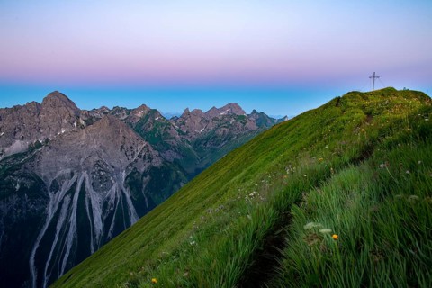 Small mountain trail with flower meadow and summit of the Uentschenspitze at sunrise