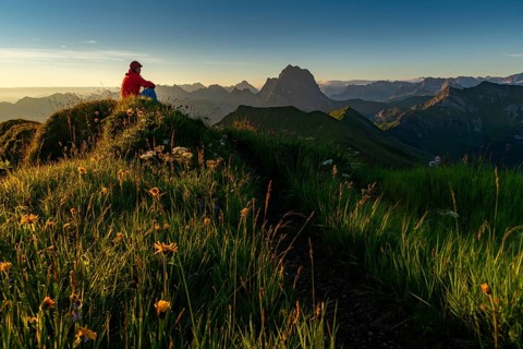 Small mountain trail with mountaineers and summits of the Allgaeuer Alps at sunrise