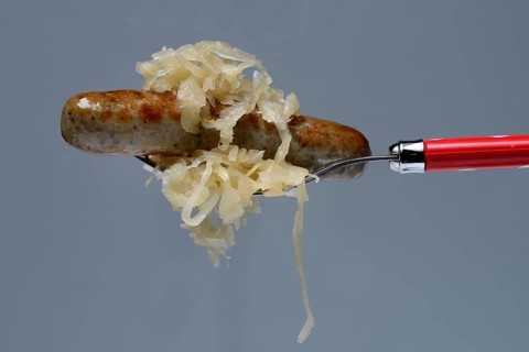 Nuremberg grilled sausages with sauerkraut on fork