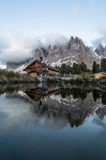 Reflection from the Furchetta mountain and the Geisler Alm hut in a pond near the Geisler Alm