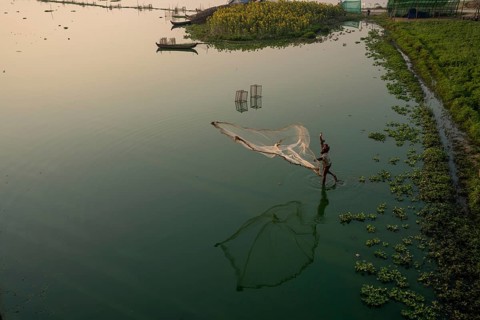Fishermen on Taung Tha Man Lake throw out a fishing net for sunrise