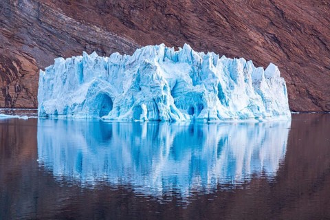 Iceberg in front of rock in fjord