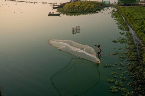 Fishermen on Taung Tha Man Lake throw out a fishing net for sunrise