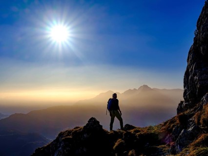 Silhouette of a mountaineer on an exposed path in the morning sun