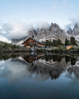 Reflection from the Furchetta mountain and the Geisler Alm hut in a pond near the Geisler Alm