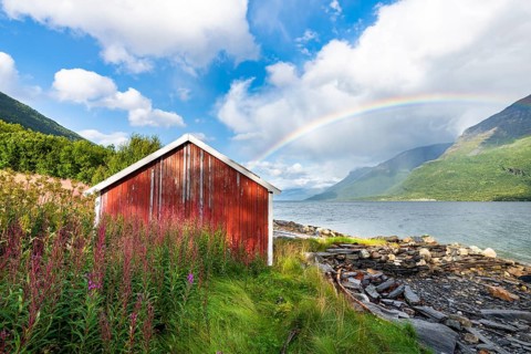 Boat hut with rainbow at the fjord