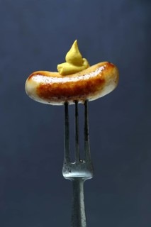 Chipolata sausages with mustard on fork