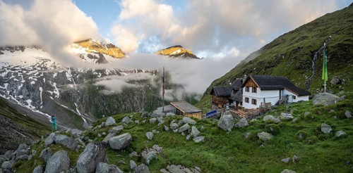 Hiker looks at mountain peaks with last sunlight