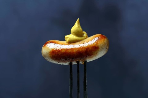 Chipolata sausages with mustard on fork