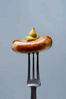 Chipolata sausages with mustard on fork