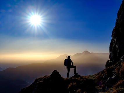 Silhouette of a mountaineer on an exposed path in the morning sun