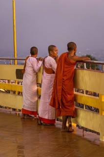 Three female Buddhist nuns at the railing of the Su Taung Pyae Pagoda