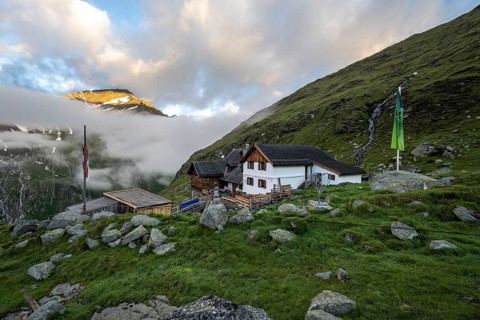 Furtschaglhaus with mountain peaks in the last sunlight and clouds