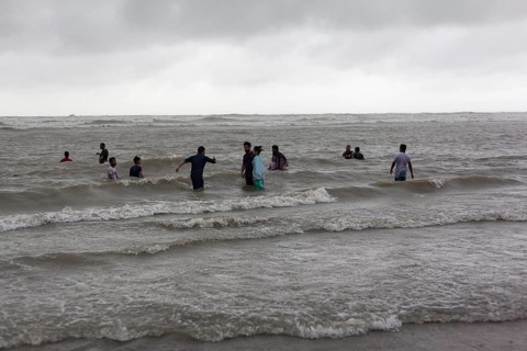 Bathers on the beach from Cox's Bazaar to monsoon rain