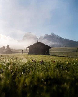 Woman looking on foggy meadow next to hut