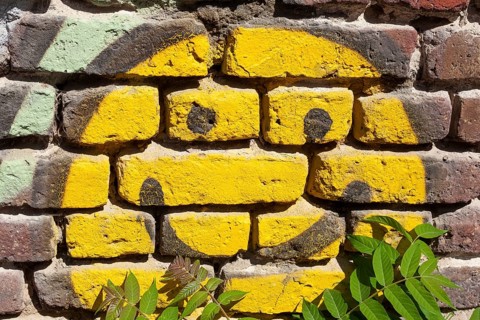 Yellow smiling smiley painted on a brick wall