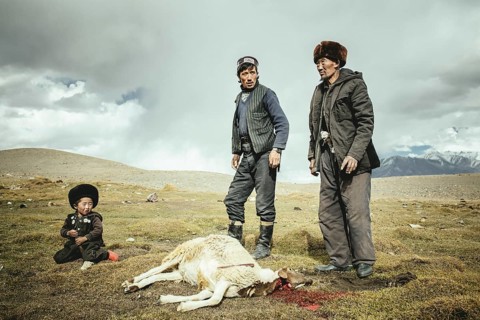 Two men and a boy after slaughtering a sheep