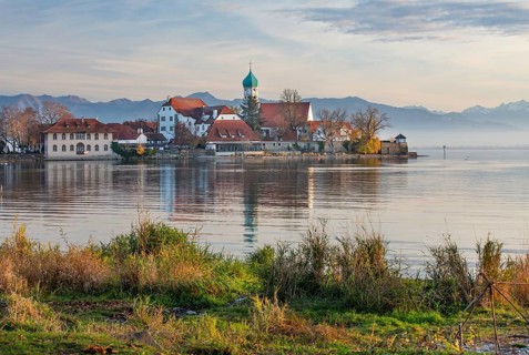 Peninsula with the parish church of St. George in front of the Alps in the evening sun
