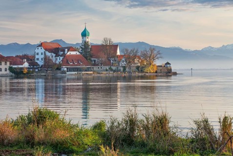 Peninsula with the parish church of St. George in front of the Alps in the evening sun