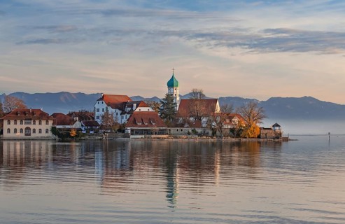 Peninsula with the parish church of St. George in front of the Alps in the evening sun