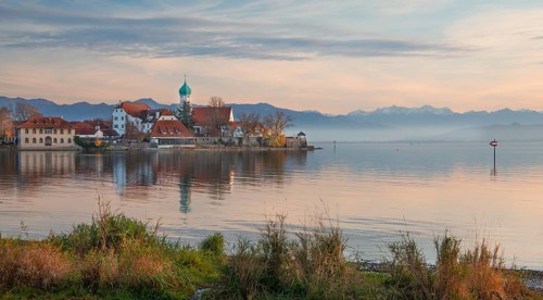 Peninsula with the parish church of St. George in front of the Alps in the evening sun